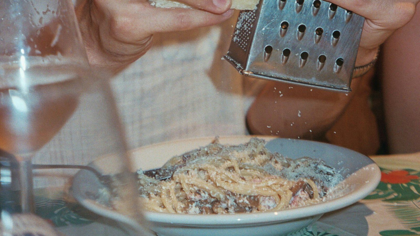A man holding a cheese grater over a plate of food
